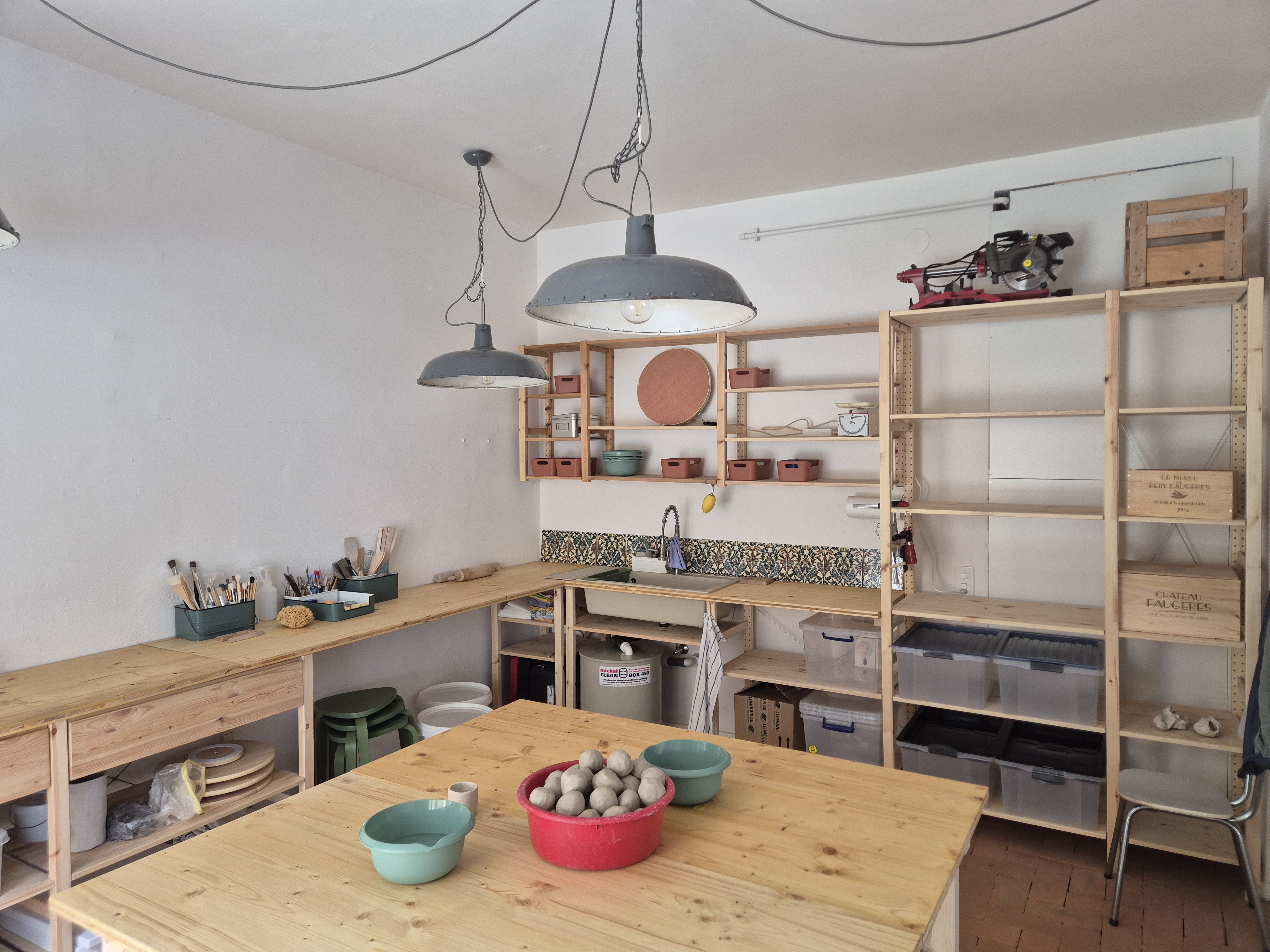 Arbeitstische mit Ton, Lampenschirmen und Regalen in der Werkstatt